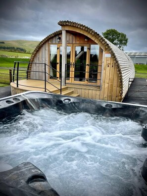 Een houten hutje met een jacuzzi ernaast.