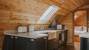 A cozy kitchen with wooden ceiling beams, a skylight, and a central island with a sink and cabinets.