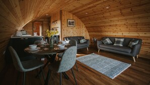 A cozy, wooden interior with a dining area, a sofa, and a kitchen.
