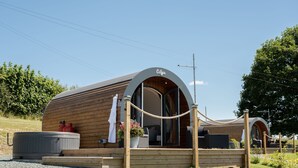 A wooden cabin with a curved roof, a small porch, and a hot tub. - Celyn -  Glamping Pod with hot Tub Sleeping 2 People (Welshpool)