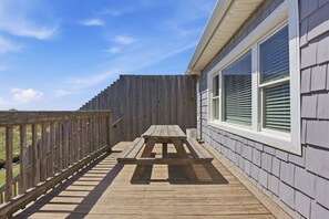 A wooden deck with a picnic table, a wooden fence, and a building with windows. - Hazels Castle Huge 2 in 1 Oceanfront House near  Pier (North Myrtle Beach)
