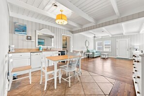 A spacious kitchen with white cabinetry, a wooden dining table, and a yellow pendant light. - Hazels Castle Huge 2 in 1 Oceanfront House near  Pier (North Myrtle Beach)