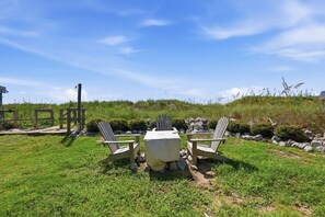 Un espace extérieur aménagé avec une table et des chaises, entouré d’herbe et de rochers.