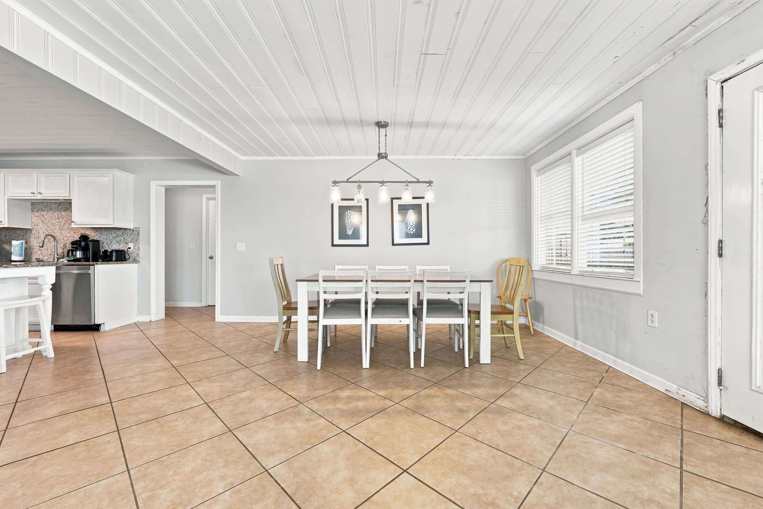 A spacious kitchen with white cabinets, a dining area with a table and chairs, and a ceiling with exposed beams.