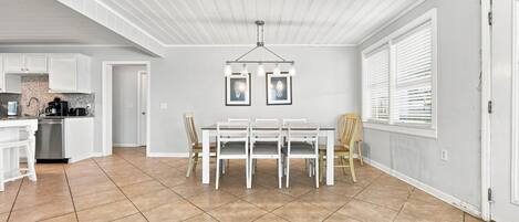 A spacious kitchen with white cabinets, a dining area with a table and chairs, and a ceiling with exposed beams.