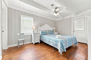 A bedroom with a bed, bedside tables, a chair, a ceiling fan, and a window with blinds. - Hazels Castle Huge 2 in 1 Oceanfront House near  Pier (North Myrtle Beach)