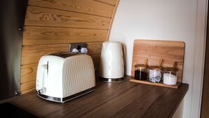 Eine Küchenzeile mit Toaster, Wasserkocher und einer Holzauslage mit Gläsern.