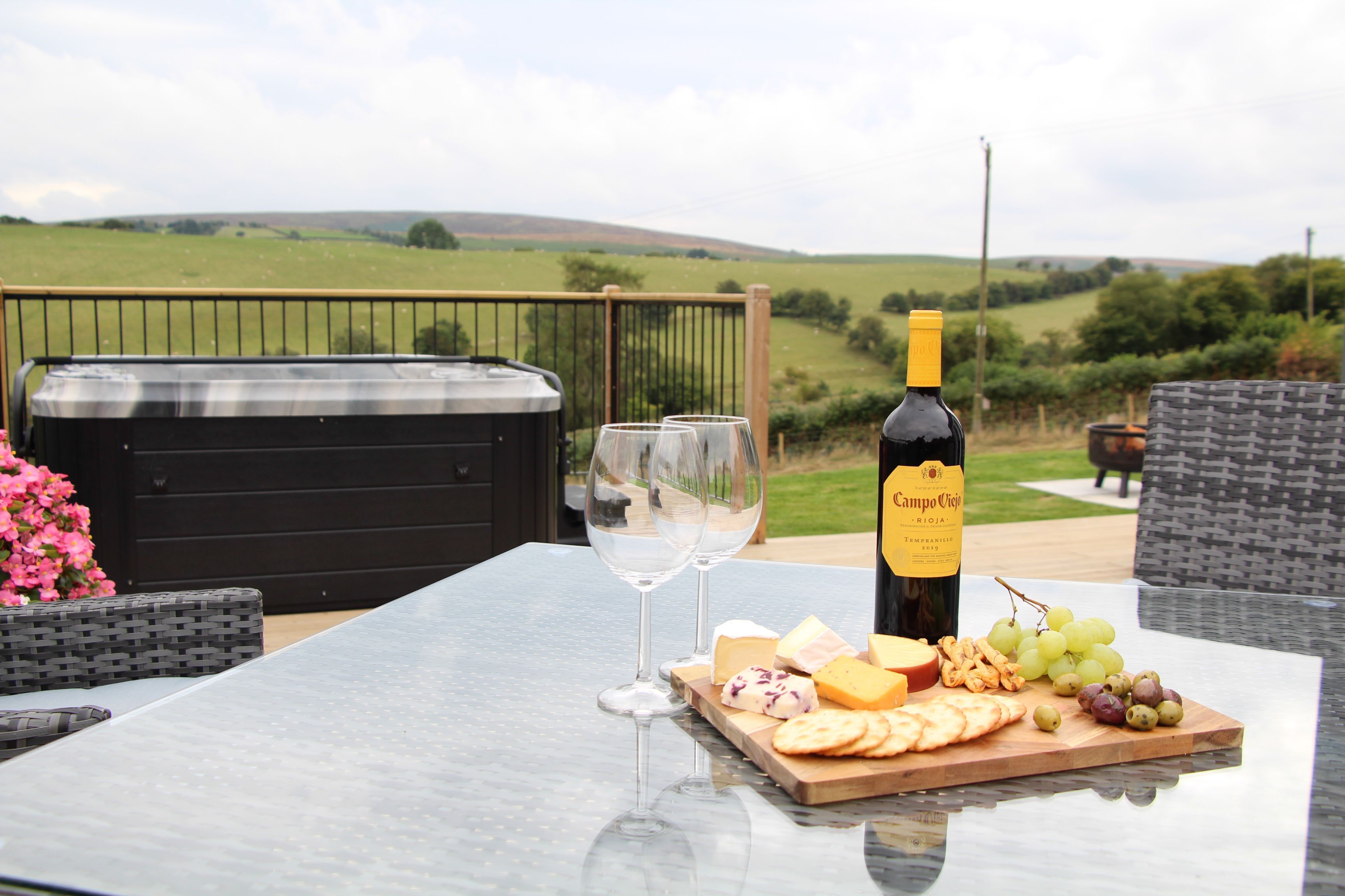 A table with a bottle of wine, glasses, cheese, and grapes.