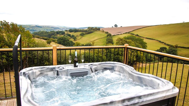A hot tub on a wooden deck with a scenic countryside view. - Cwm Heulog -  Cabin with Hot Tub Sleeping 4, Pet Friendly (Knighton)