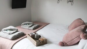 A neatly made bed with towels, a tray with cups and a bottle, and a wall with a motivational quote. - Cwm Heulog -  Cabin with Hot Tub Sleeping 4, Pet Friendly (Knighton)