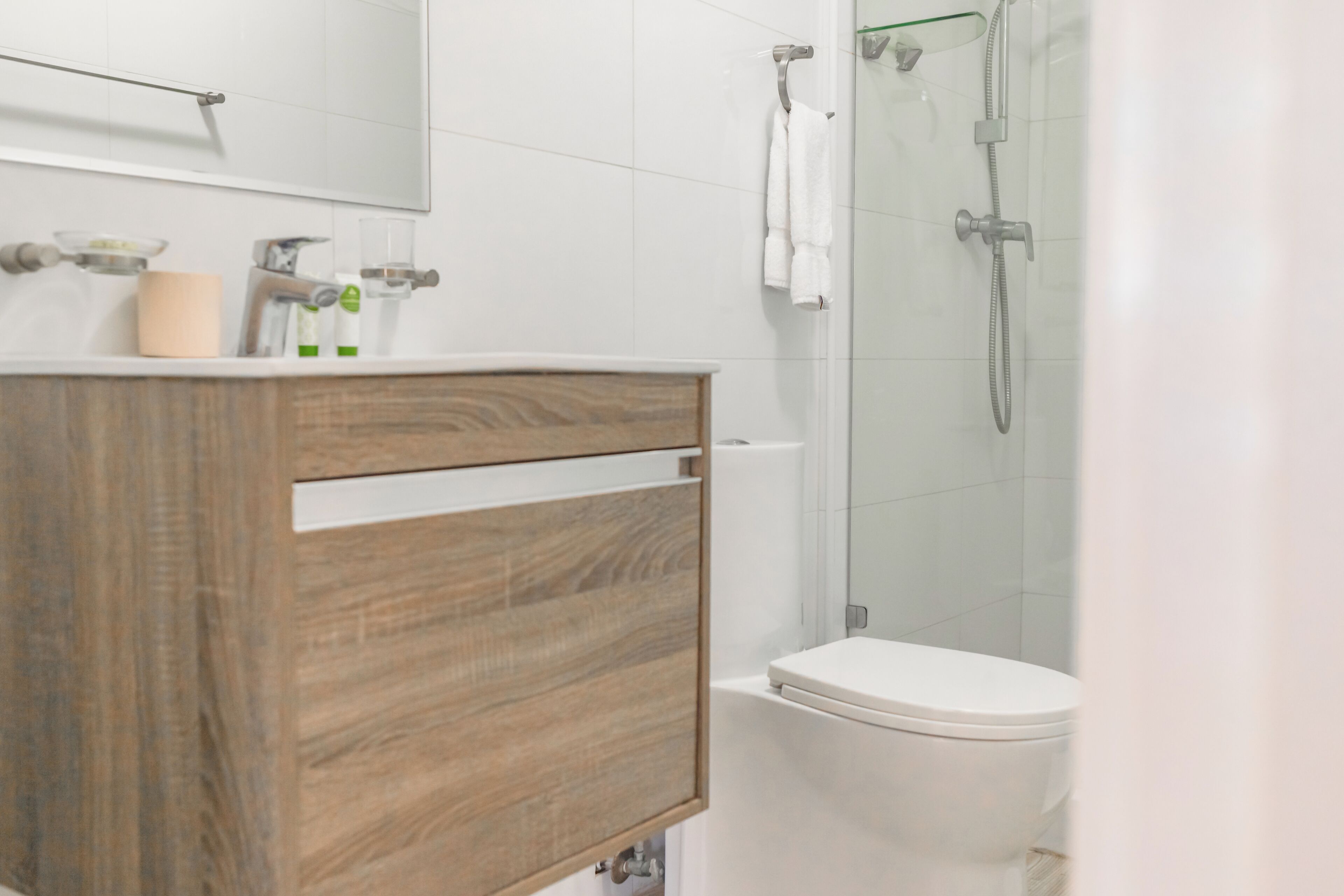 A bathroom with a wooden vanity, a toilet, and a glass shower enclosure.
