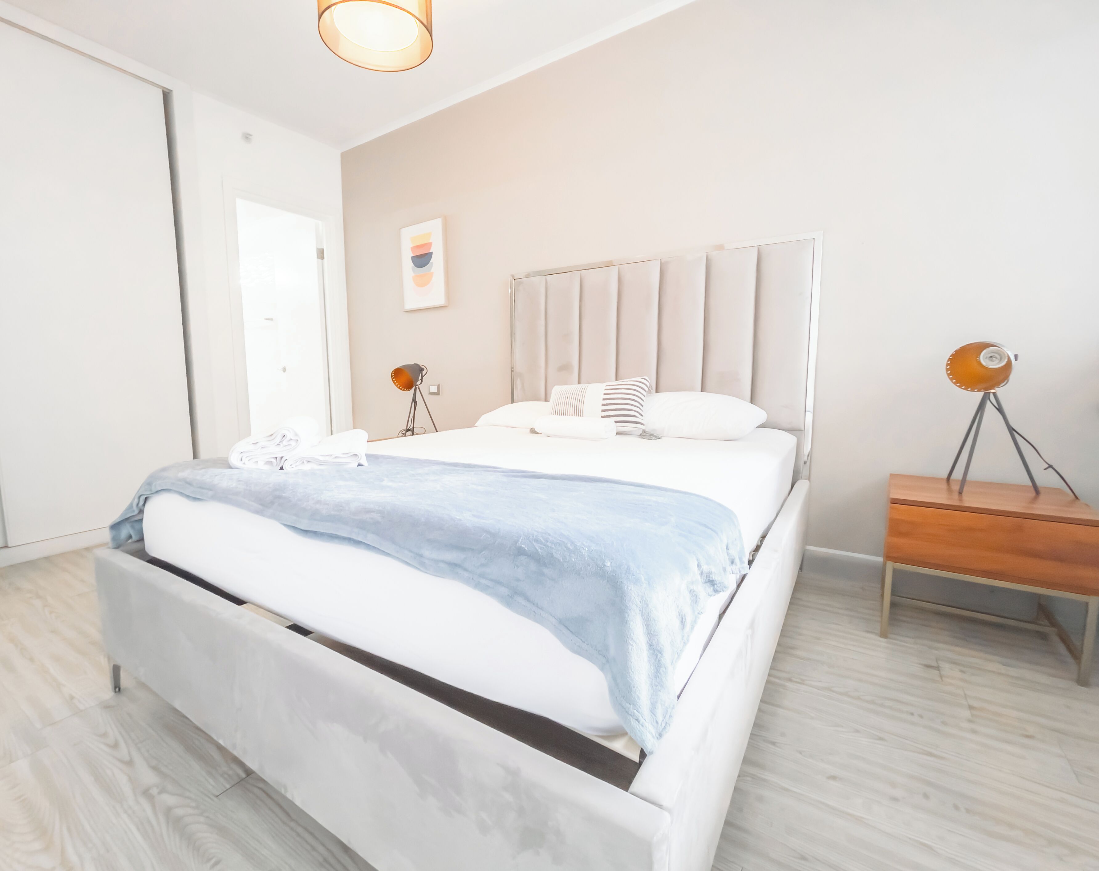 A modern bedroom with a bed, bedside table, and a lamp.