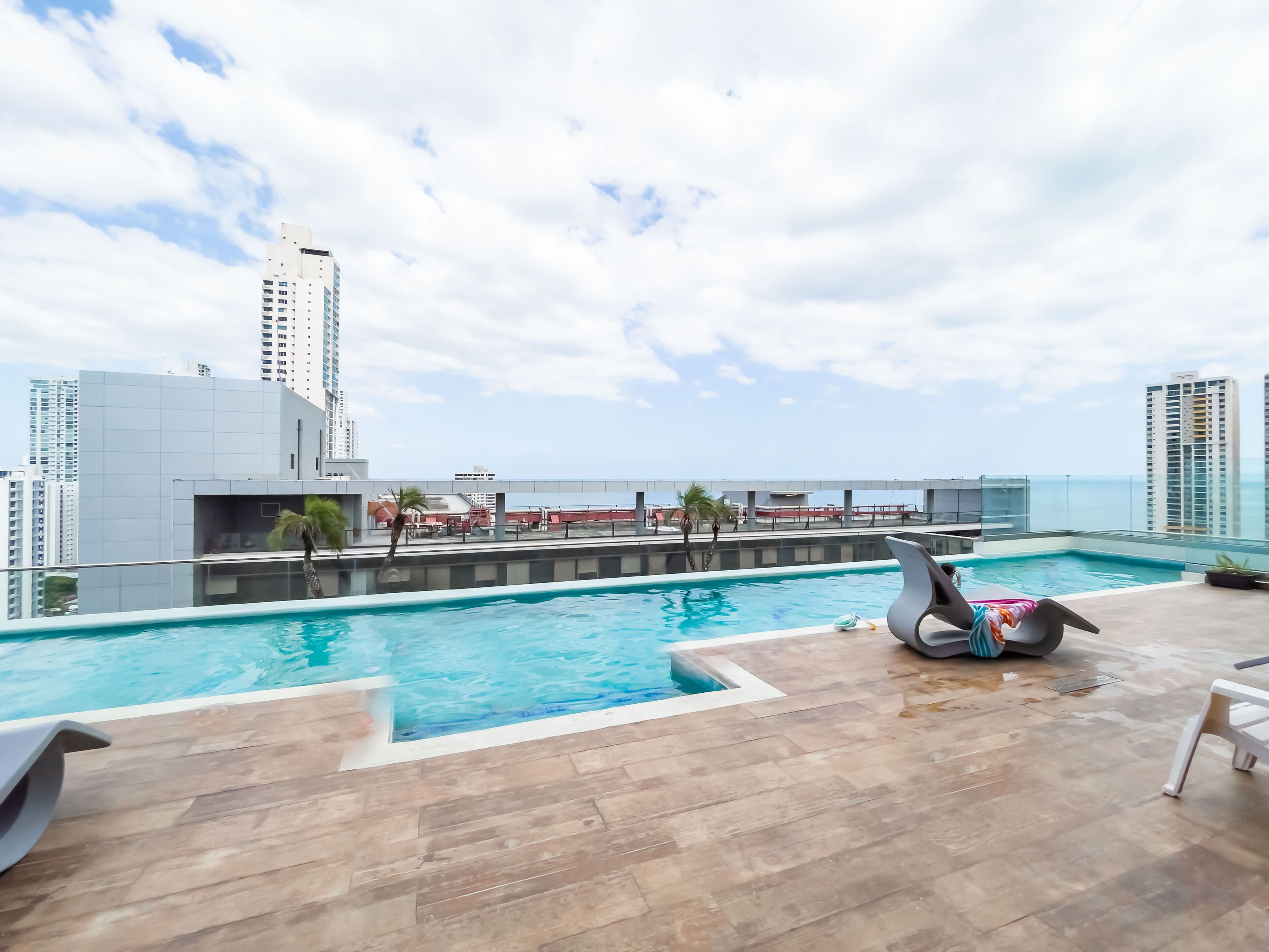 Una piscina en la azotea con vistas al océano y edificios altos.