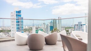Un balcón moderno con sillas blancas y vistas a la ciudad.