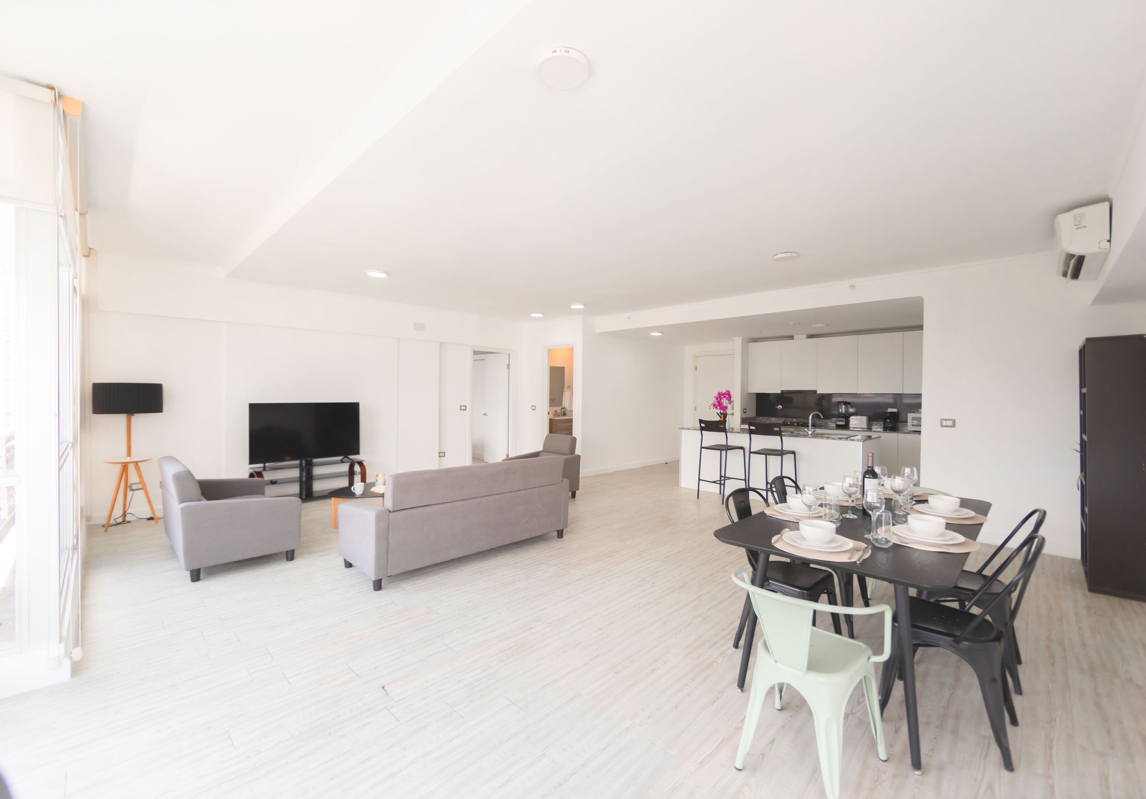 Een moderne woonkamer met een bank, televisie en een eethoek met stoelen en een tafel.