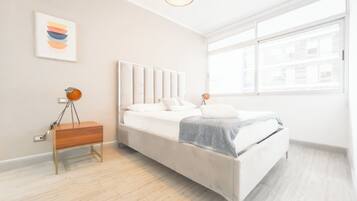 A modern bedroom with a bed, bedside table, lamp, and artwork on the wall.