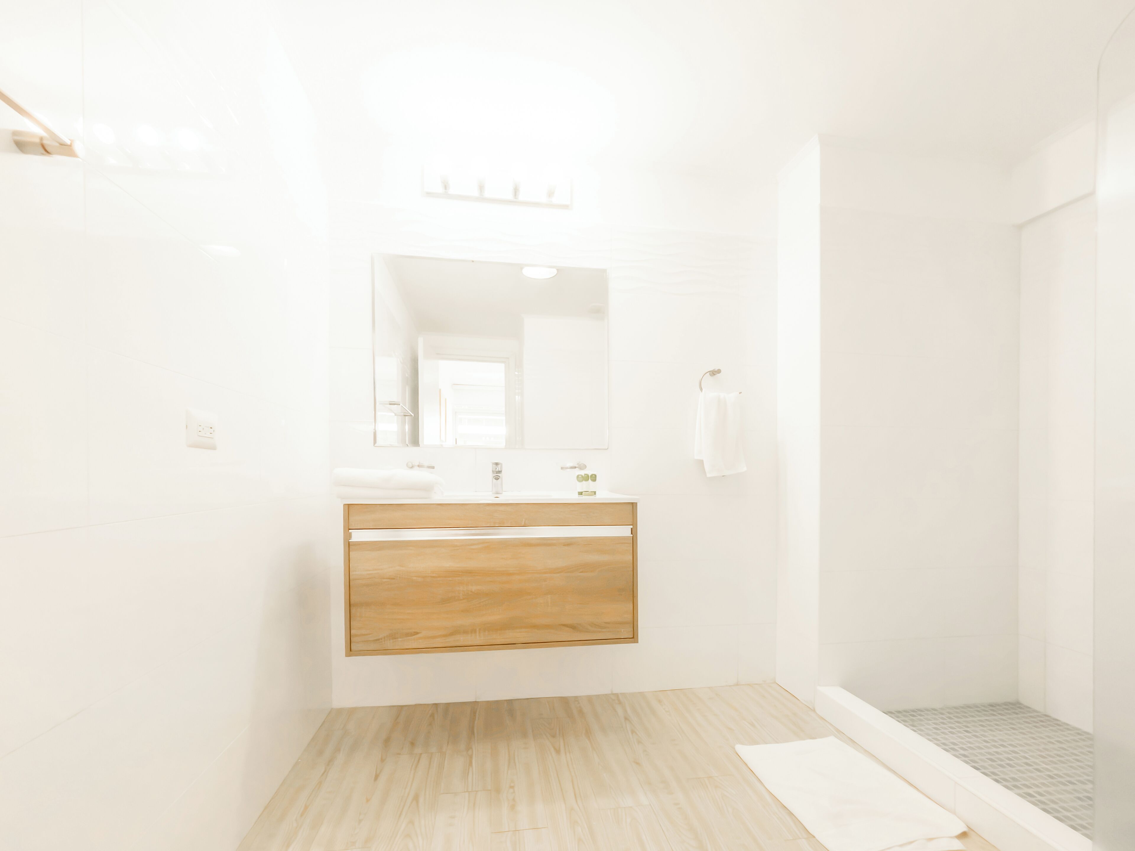 A modern bathroom with a wooden vanity, a large mirror, and a shower area.