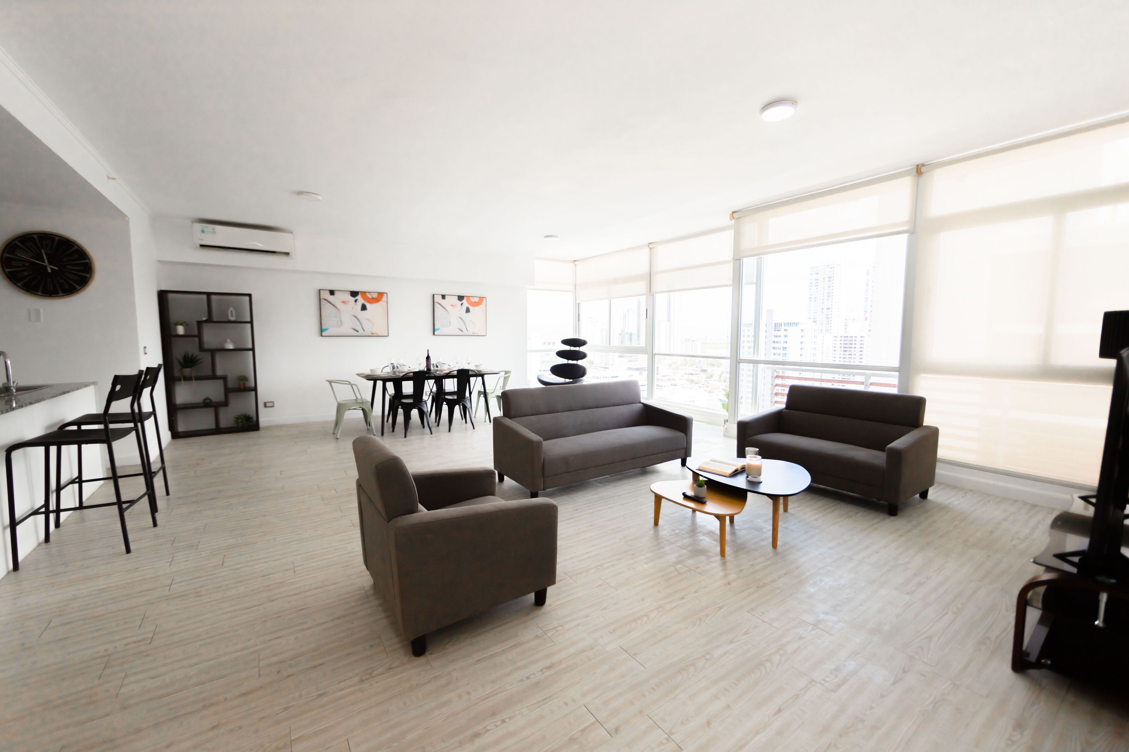 Una sala de estar moderna con sofá, sillones, una mesa de centro y un comedor con sillas y una mesa.