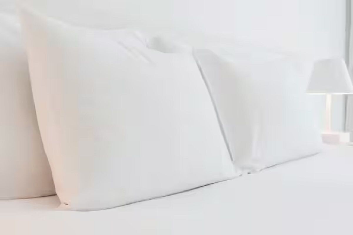 Ein Bett mit weißer Bettwäsche und Kissen.