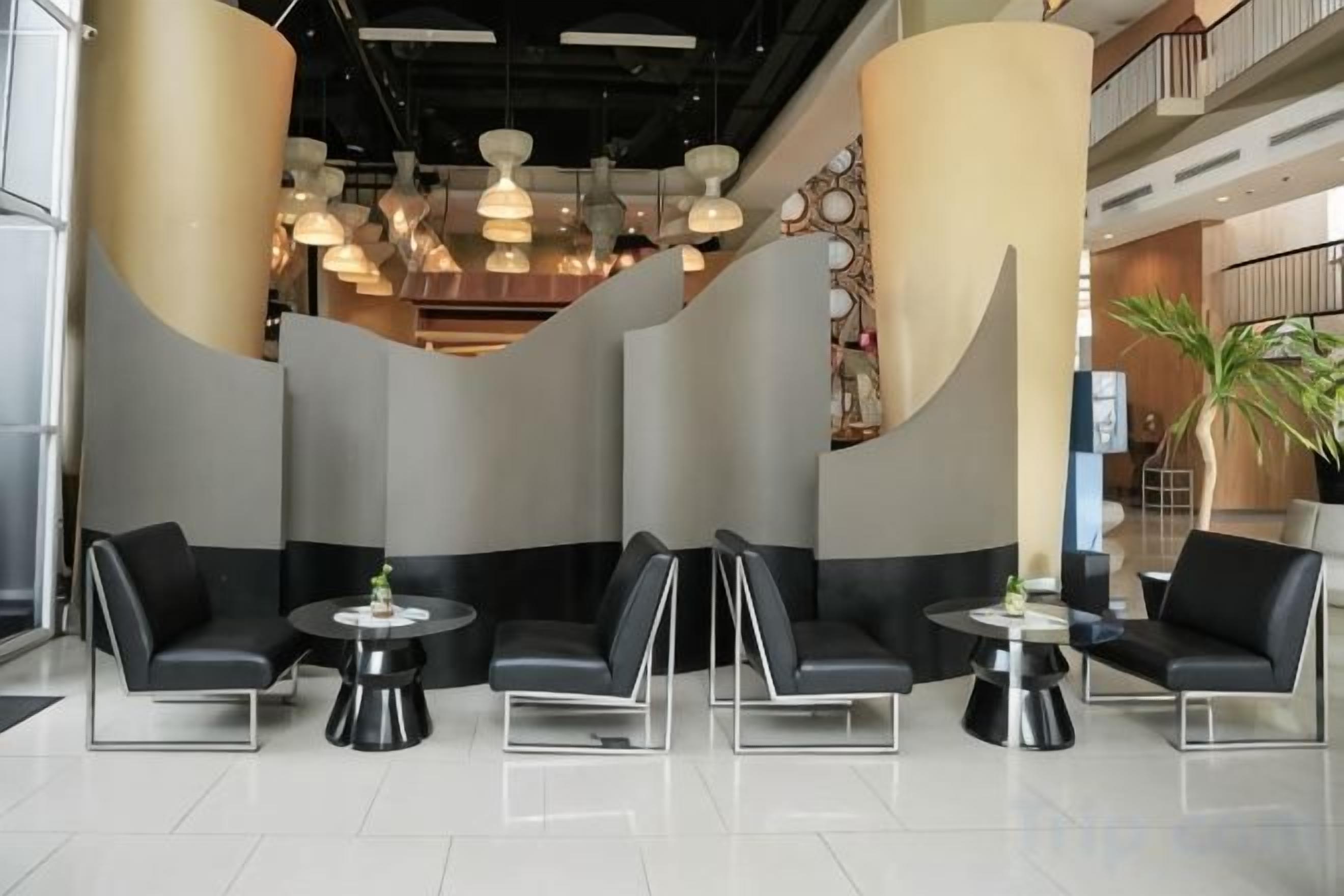 Ein stilvoller Lounge-Bereich mit Sitzgelegenheiten und Tischen, einer großen Säule und Pendelleuchten.