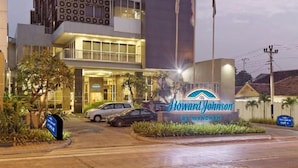 Un hôtel Howard Johnson doté d’une façade moderne, de plusieurs étages et d’une enseigne bien visible.