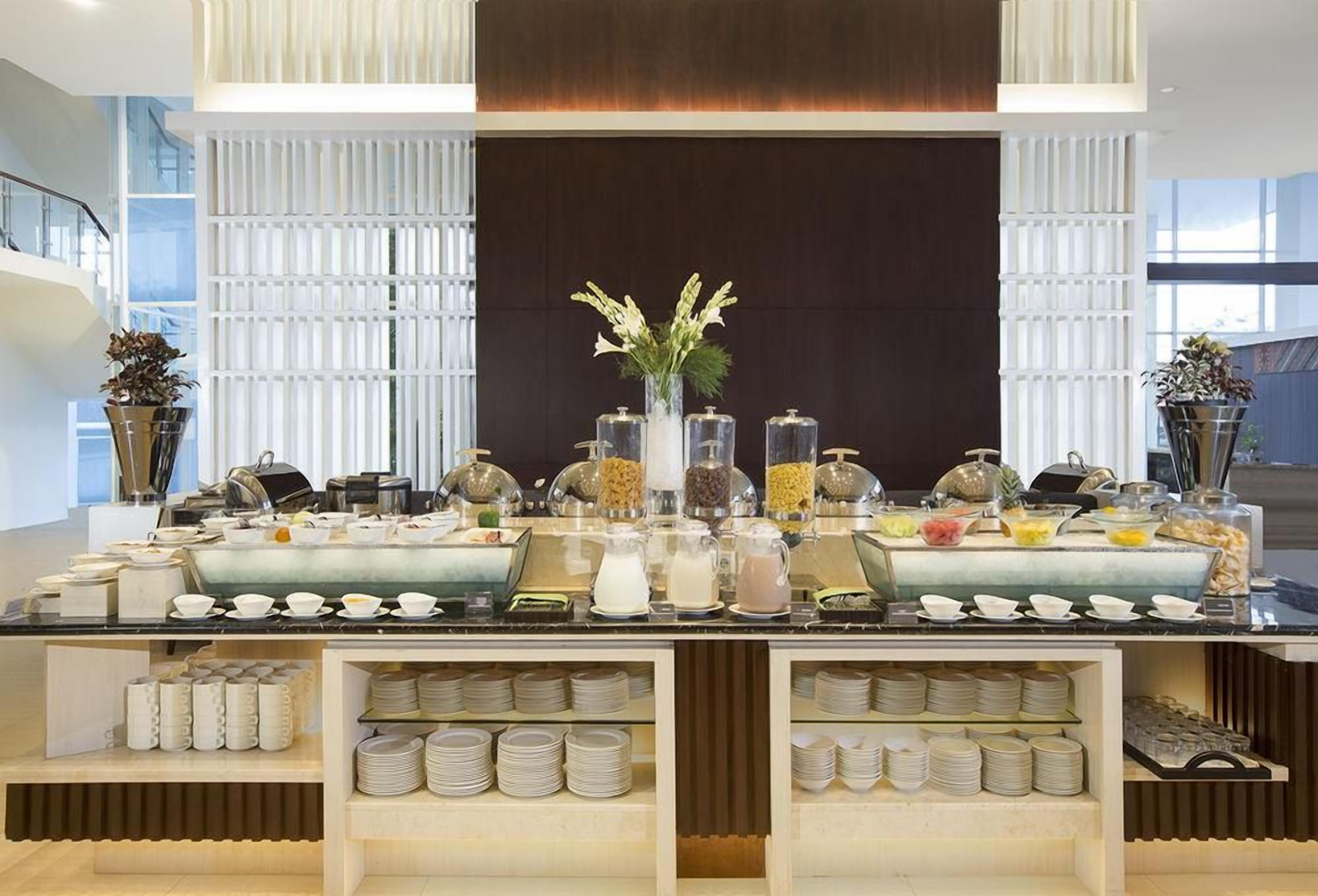 Un buffet proposant une variété de plats et d’accompagnements, un vase rempli de fleurs, ainsi que des assiettes et des bols disposés avec soin.