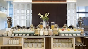 Un buffet proposant une variété de plats et d’accompagnements, un vase rempli de fleurs, ainsi que des assiettes et des bols disposés avec soin.