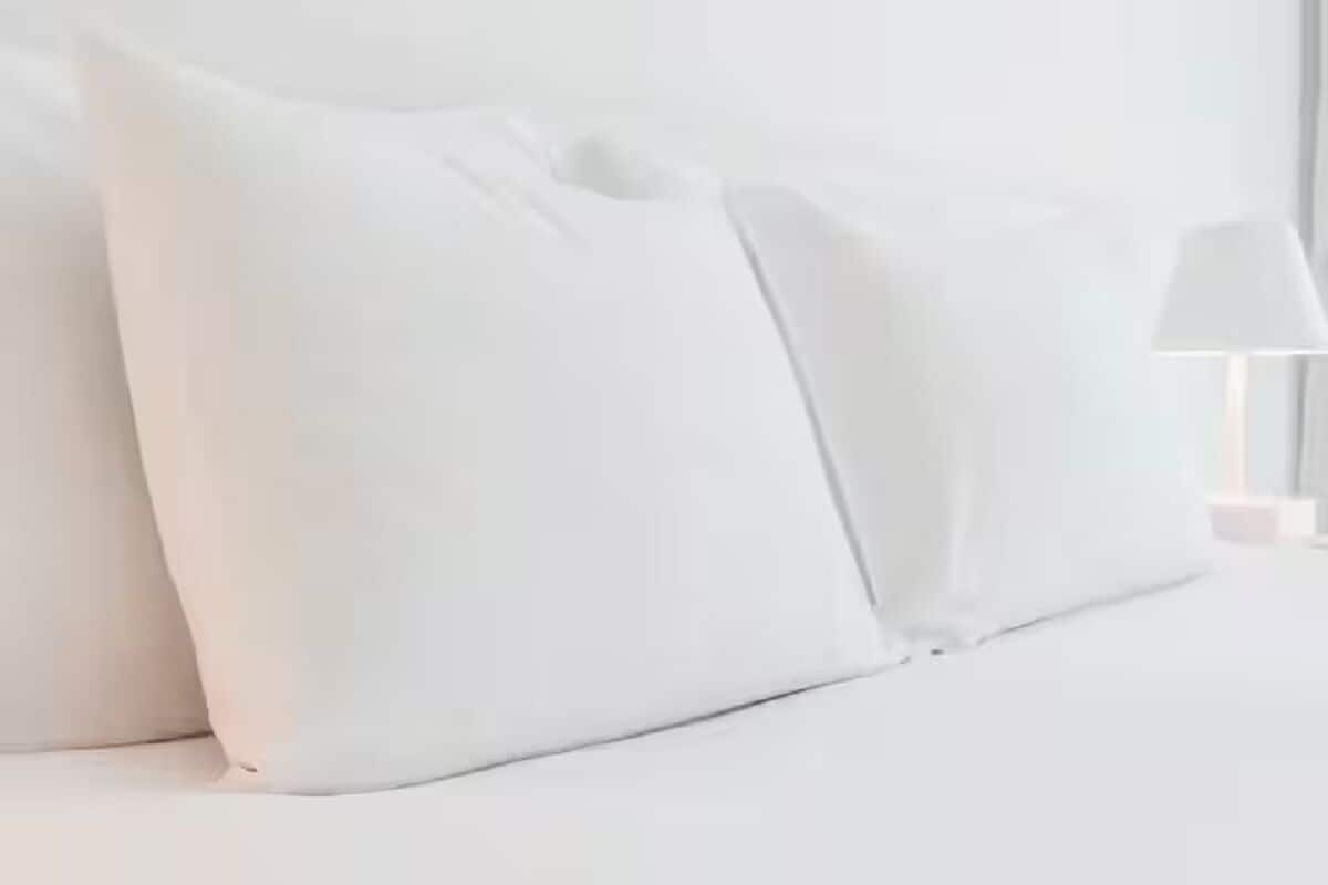 Una cama con ropa de cama y almohadas blancas.