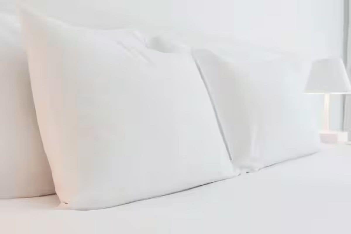 Una cama con ropa de cama y almohadas blancas.