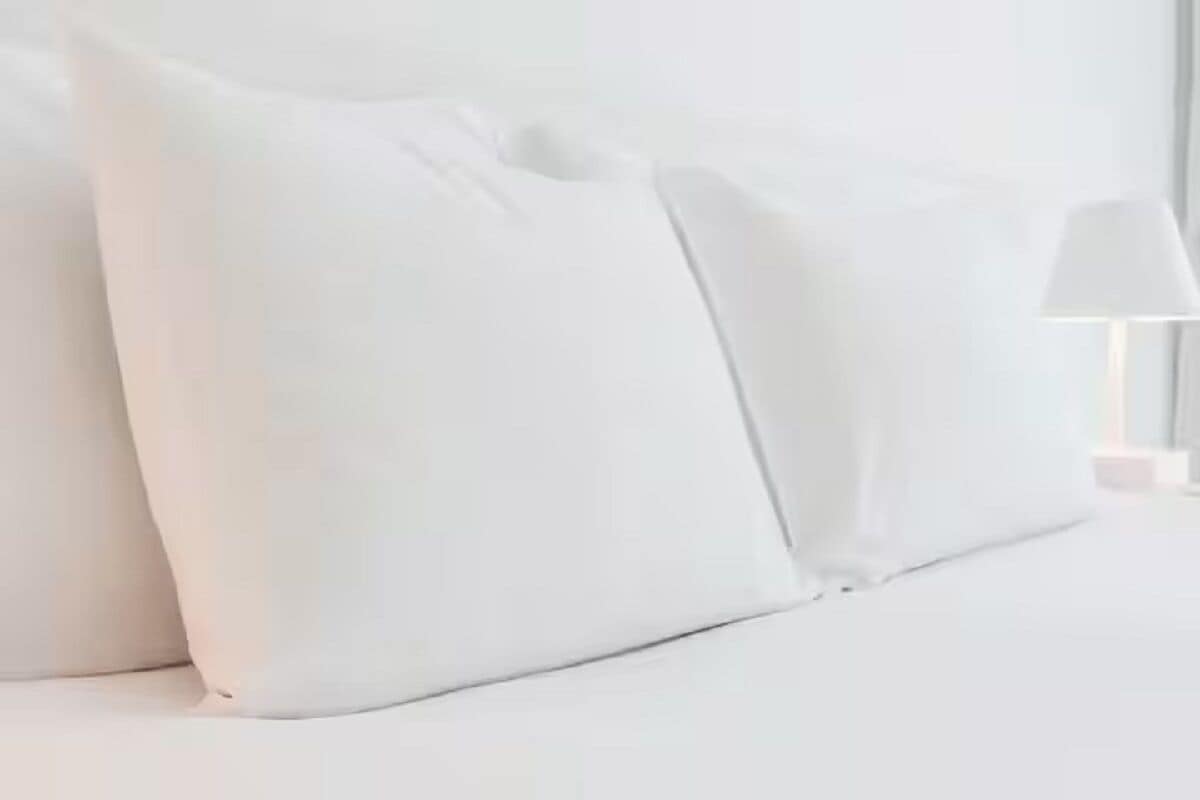Ein Bett mit weißer Bettwäsche und Kissen.