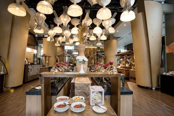 A restaurant interior with multiple hanging light fixtures, a central table with dishes, and a modern design.