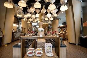 Interior de restaurante con múltiples lámparas colgantes, una mesa central con platos y un diseño moderno.