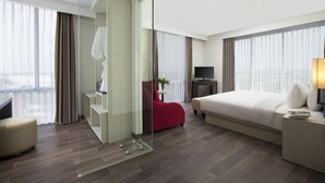 Une chambre d’hôtel équipée d’un lit, d’une télévision, d’un bureau, d’une chaise et d’une cloison en verre.
