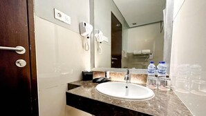 Une salle de bain avec un comptoir en marbre, un lavabo, un miroir, un porte-serviettes et un téléphone.