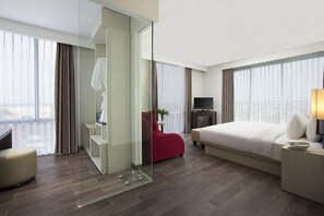 Une chambre d’hôtel équipée d’un lit, d’une télévision, d’un bureau, d’une chaise et d’une cloison en verre.