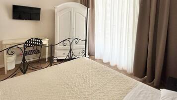 Un dormitorio con una cama, un armario, un televisor, una silla y cortinas.