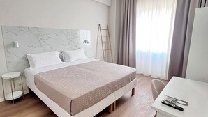 A modern hotel room with a bed, bedside tables, a desk, and a view of the outdoors. - Porta Amari (Palermo)