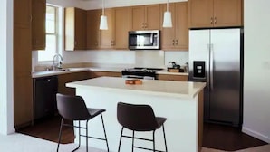A modern kitchen with wooden cabinets, stainless steel appliances, and pendant lighting. - Family Friendly 3BR w/Mt views, Close to Beach (Waianae)
