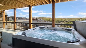 Ett bubbelbad under en träpergola med utsikt över ett bostadsområde.