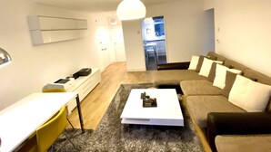 A modern living room with a sofa, coffee table, and a dining area with a yellow chair. - Luxurious Living in the Heart of Bromley (Bromley)