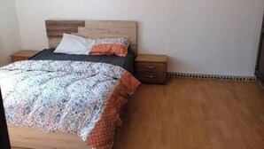 A bedroom with a wooden bed, a patterned bedspread, a white pillow, and a small wooden nightstand with drawers. - A beautiful apartment with traditional architecture 3 minutes from bouregreg (Salé)