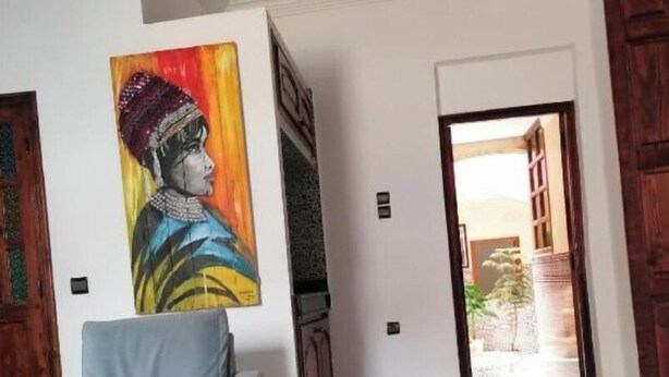 A living room with a sofa, a painting on the wall, and a view of the outside. - A beautiful apartment with traditional architecture 3 minutes from bouregreg (Salé)