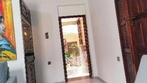 A hallway with a white sofa, a painting on the wall, and a wooden door. - A beautiful apartment with traditional architecture 3 minutes from bouregreg (Salé)
