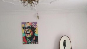 A room with a bed, a wooden dresser with a mirror, and a colorful painting on the wall. - A beautiful apartment with traditional architecture 3 minutes from bouregreg (Salé)