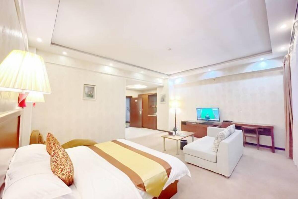 Ein Hotelzimmer mit Bett, Sofa, Schreibtisch, Fernseher und Lampe.