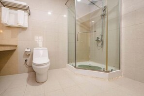Une salle de bain comprenant des toilettes, une douche à parois de verre et un porte-serviettes.