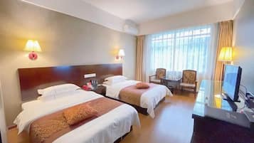 A hotel room with two beds, a desk with a computer, a chair, and a TV.