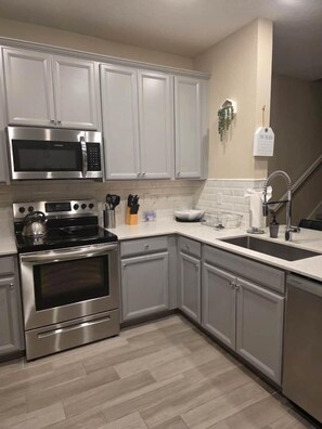 A modern kitchen with stainless steel appliances, grey cabinetry, a white countertop, and a sink. - 3BR/2.5BA Home - 2 Queen+2 Single Bds - North Jax (Jacksonville)