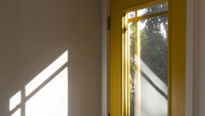 Um quarto com porta amarela, uma mesa redonda e duas cadeiras.