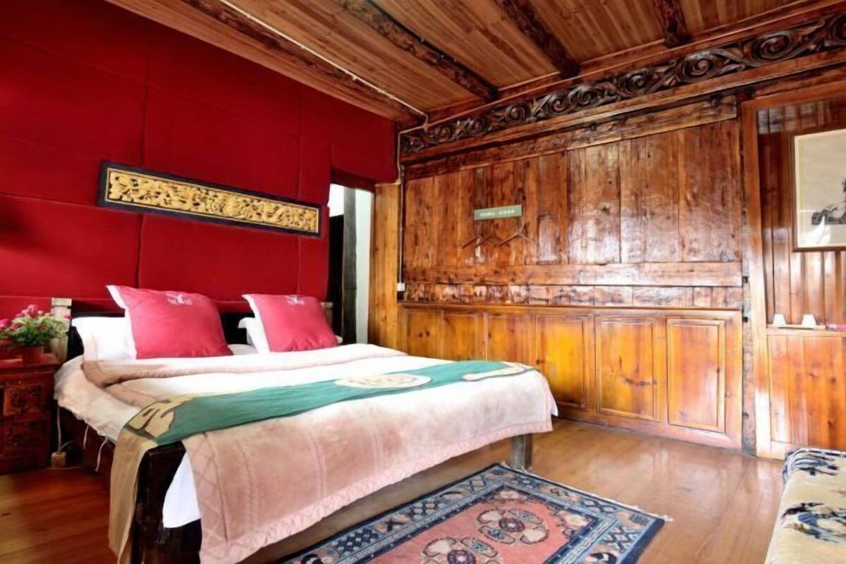 A wooden-paneled room with a bed, a red wall, and a decorative panel.